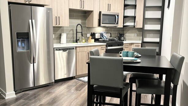 Una cocina moderna con electrodomésticos de acero inoxidable, armarios de madera y un comedor con mesa y sillas.