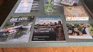 A kitchen counter with brochures, a vase with flowers, and a coffee maker. - Beautiful Lake home-5 minute walk to the Public Beach Area, (Rochester)