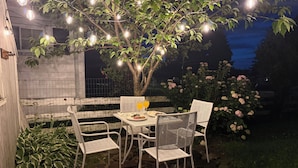 An outdoor patio with a table and chairs, string lights, and a tree. - Beautiful Lake home-5 minute walk to the Public Beach Area, (Rochester)
