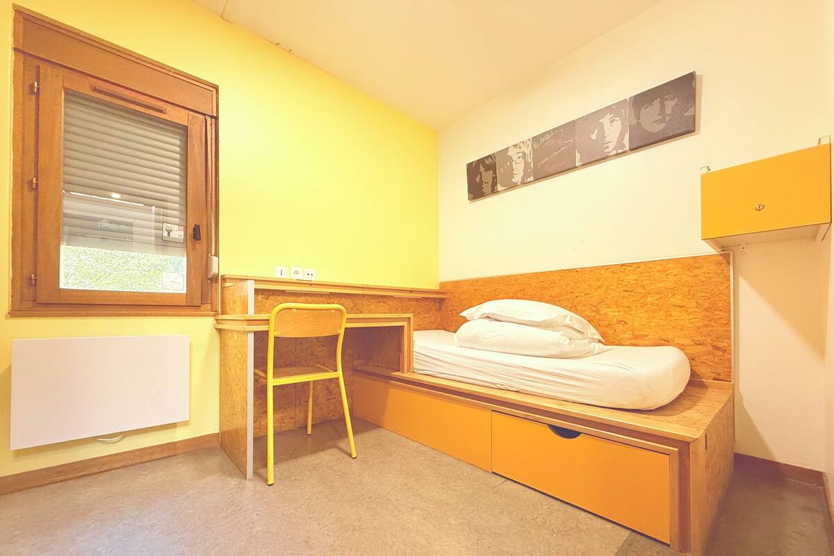 Una habitación pequeña con cama, escritorio y silla.