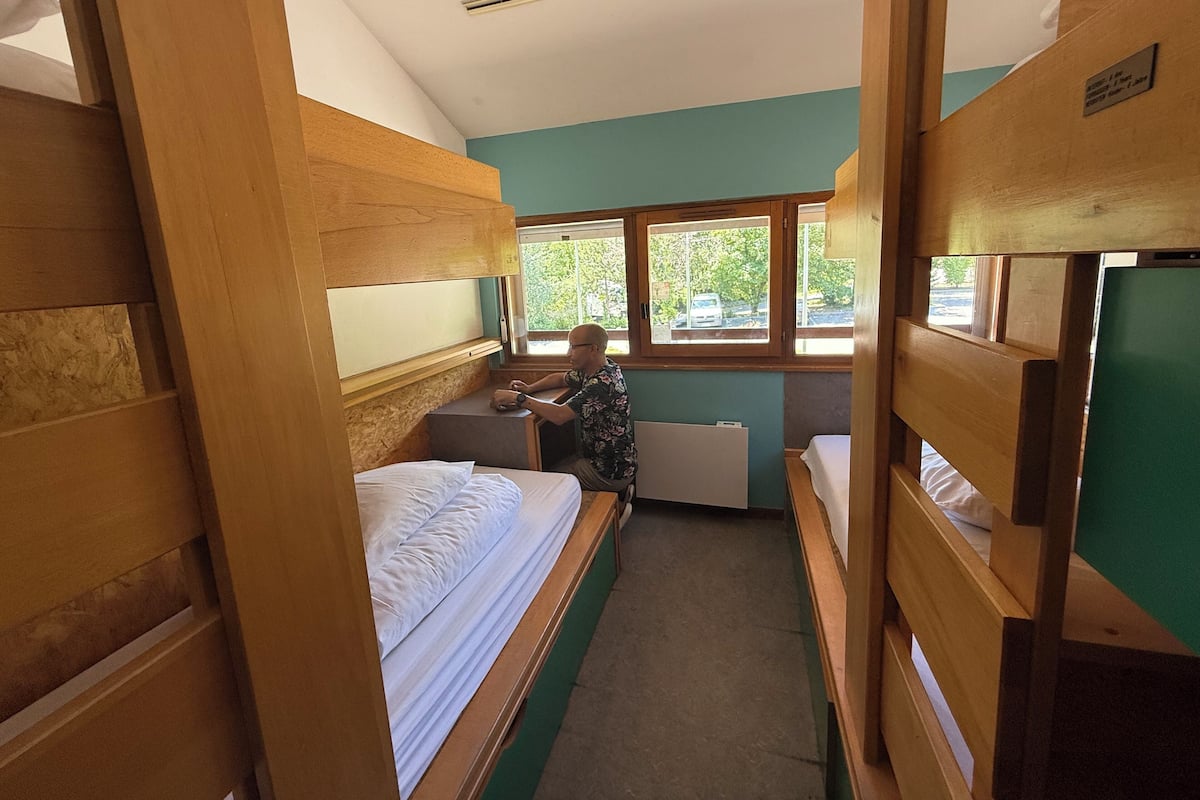 Una habitación pequeña con literas, un escritorio y una ventana con vistas al verdor.