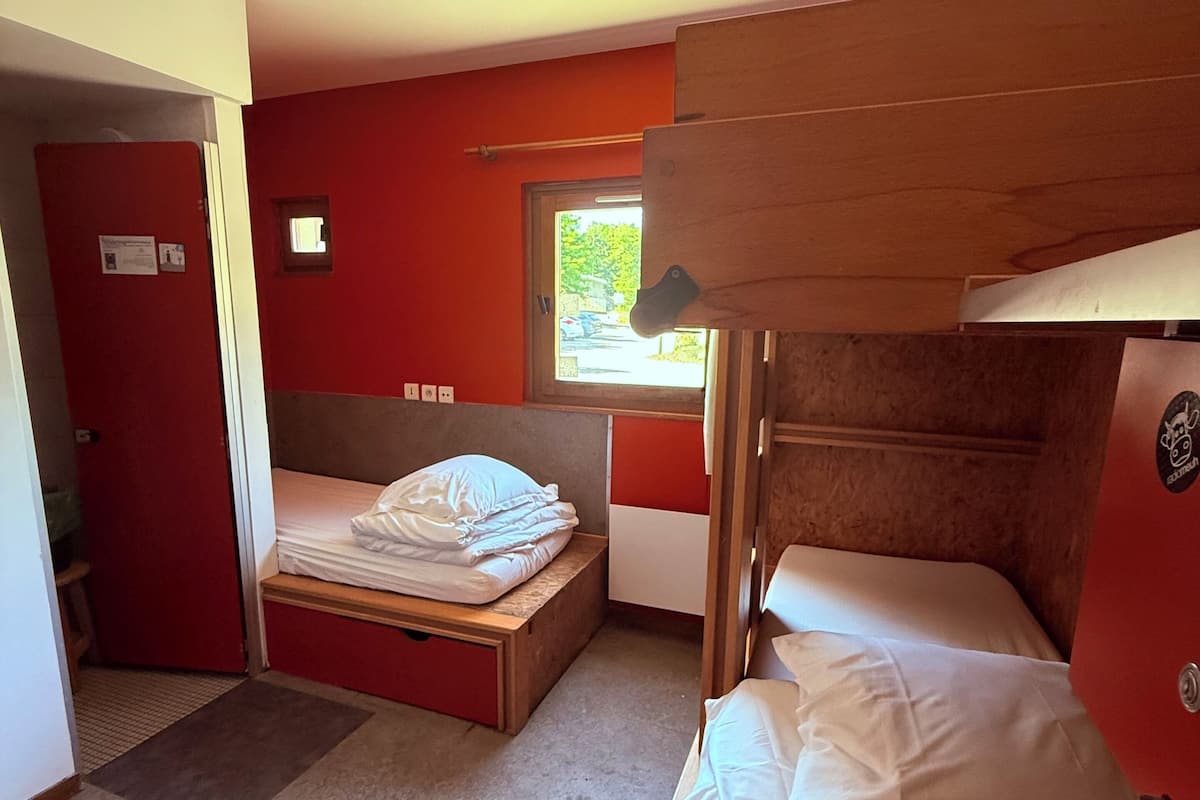 Un dormitorio con literas, una ventana pequeña y una puerta.