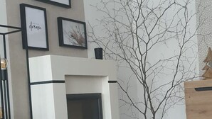 Een moderne woonkamer met een open haard, een houten bijzettafeltje met kaarsen, en een minimalistische inrichting.