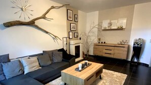 Een moderne woonkamer met een donkergrijze bank, een houten salontafel en een open haard.