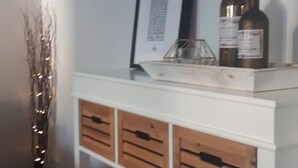 Een witte consoles van een bijzettafel met houten lades, een ingelijst certificaat en twee flessen erop.