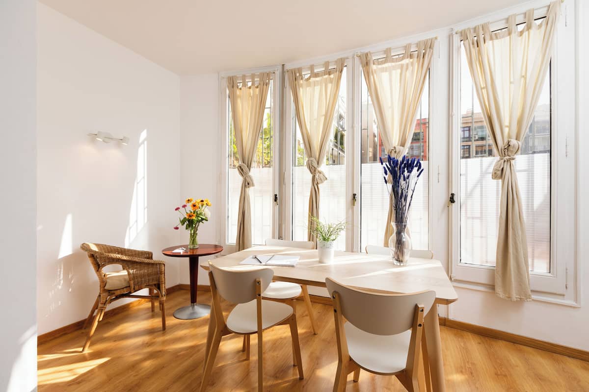 A room with a round table, four chairs, and a vase with flowers.