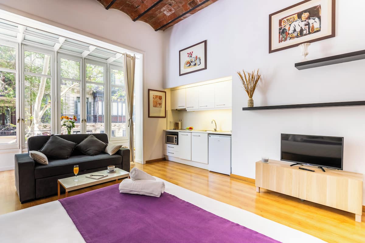A modern living room with a sofa, coffee table, and a flat-screen TV on a wooden cabinet.