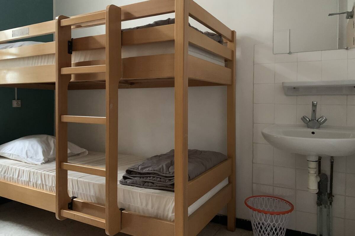 Ein Stockbett mit Holzrahmen, ein weißes Waschbecken mit Chromarmatur und ein Basketballkorb.