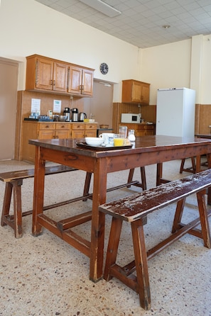 Une cuisine avec des meubles de rangement en bois, une table en bois et un banc.