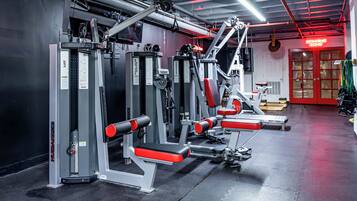 A gym with weight machines, benches, and a red door labeled "SPANNING ZONE".