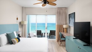 Habitación de hotel con una cama grande, televisión, escritorio y vista al océano.