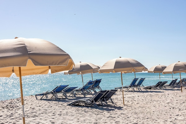 On the beach, white sand, sun loungers, beach towels