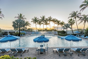 A beach with rows of sun loungers and umbrellas, a clear sky, and the ocean in the background. at Sherry Frontenac Oceanfront Hotel