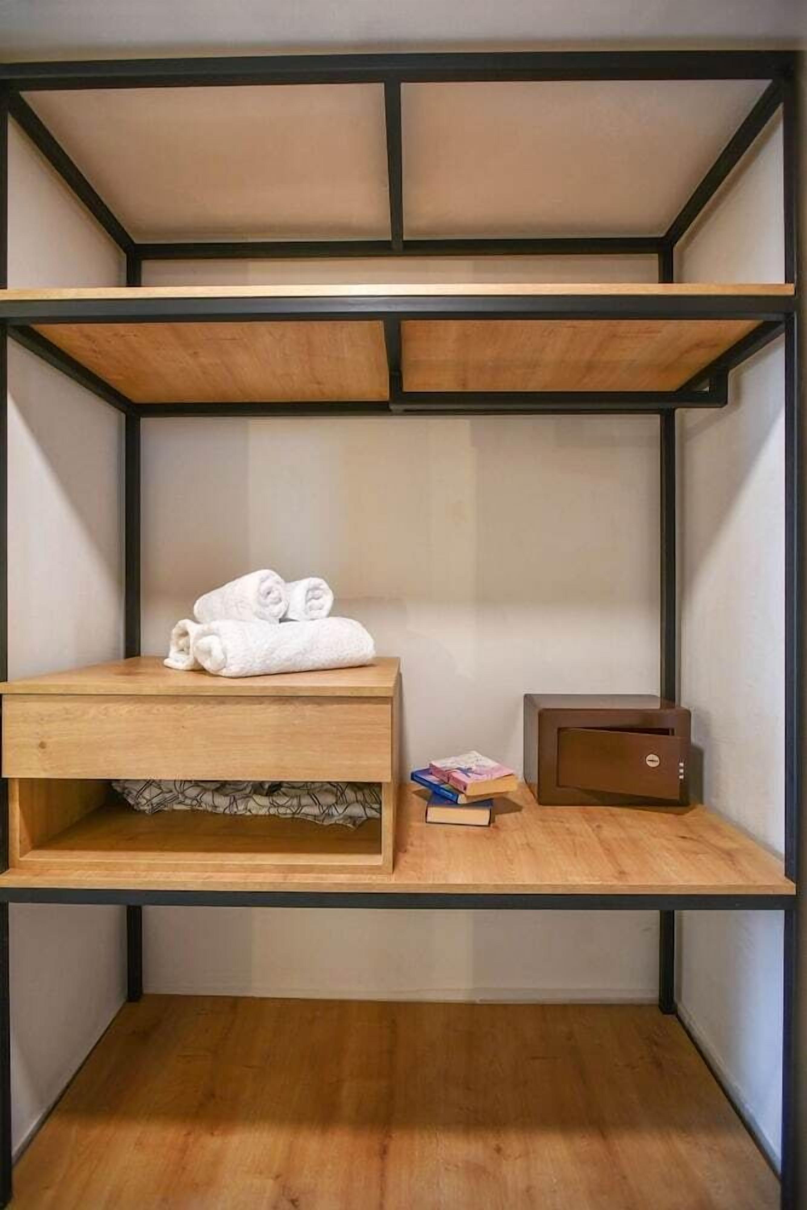 A bunk bed with a wooden headboard, a small bedside table with a book, and a brown electronic device on the lower shelf.