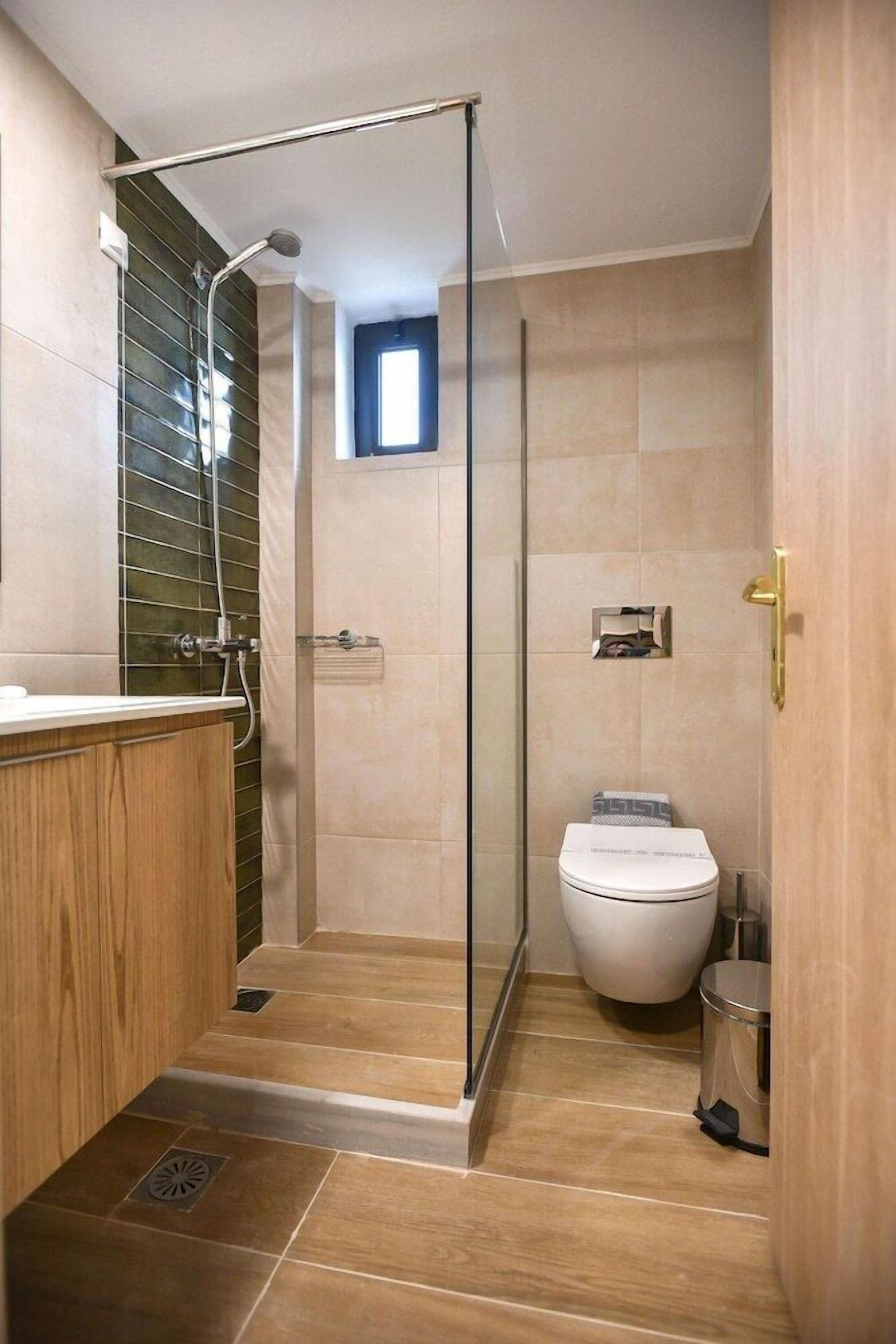 A modern bathroom with a glass shower enclosure, a toilet, and a sink with a wooden vanity.