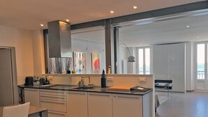 A modern kitchen with a large island, built-in appliances, and a large window providing natural light. - 20. Bright & lovely apt with incredible sea view, in the heart of the old town (Antibes)