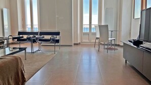 A spacious living area with a sofa, chairs, a TV, and large windows offering a view of the sea. - 20. Bright & lovely apt with incredible sea view, in the heart of the old town (Antibes)