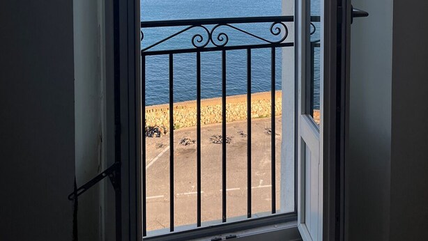 A view from a balcony with a railing, overlooking a body of water and a rocky shoreline. - 20. Bright & lovely apt with incredible sea view, in the heart of the old town (Antibes)