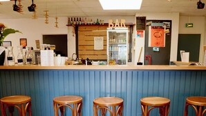 Un espace bar avec des tabourets, un réfrigérateur et un tableau affichant le menu.