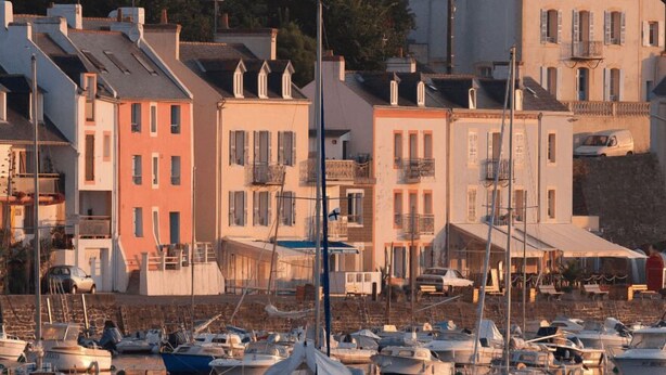 Un port de plaisance où sont amarrés des bateaux, entouré d’immeubles à plusieurs étages dotés de balcons.