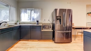A modern kitchen with dark cabinets, a stainless steel refrigerator, a microwave, and a coffee maker on the counter. - Private Apartment with pool, 5 min to downtown (Tulsa)