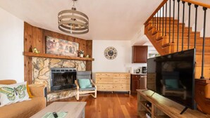 A living room with a fireplace, wooden furniture, a TV, and a staircase.