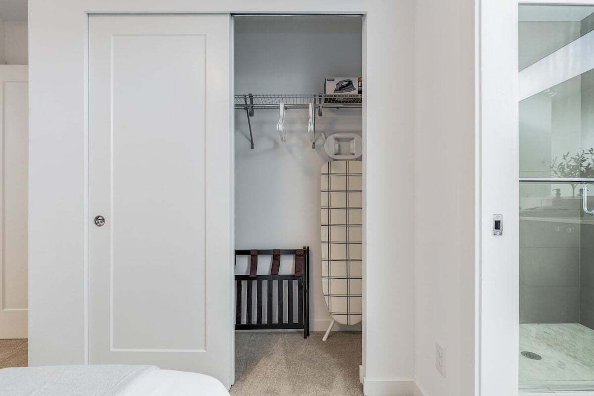 A bedroom with a white door, a bed, a crib, and a glass shower enclosure.