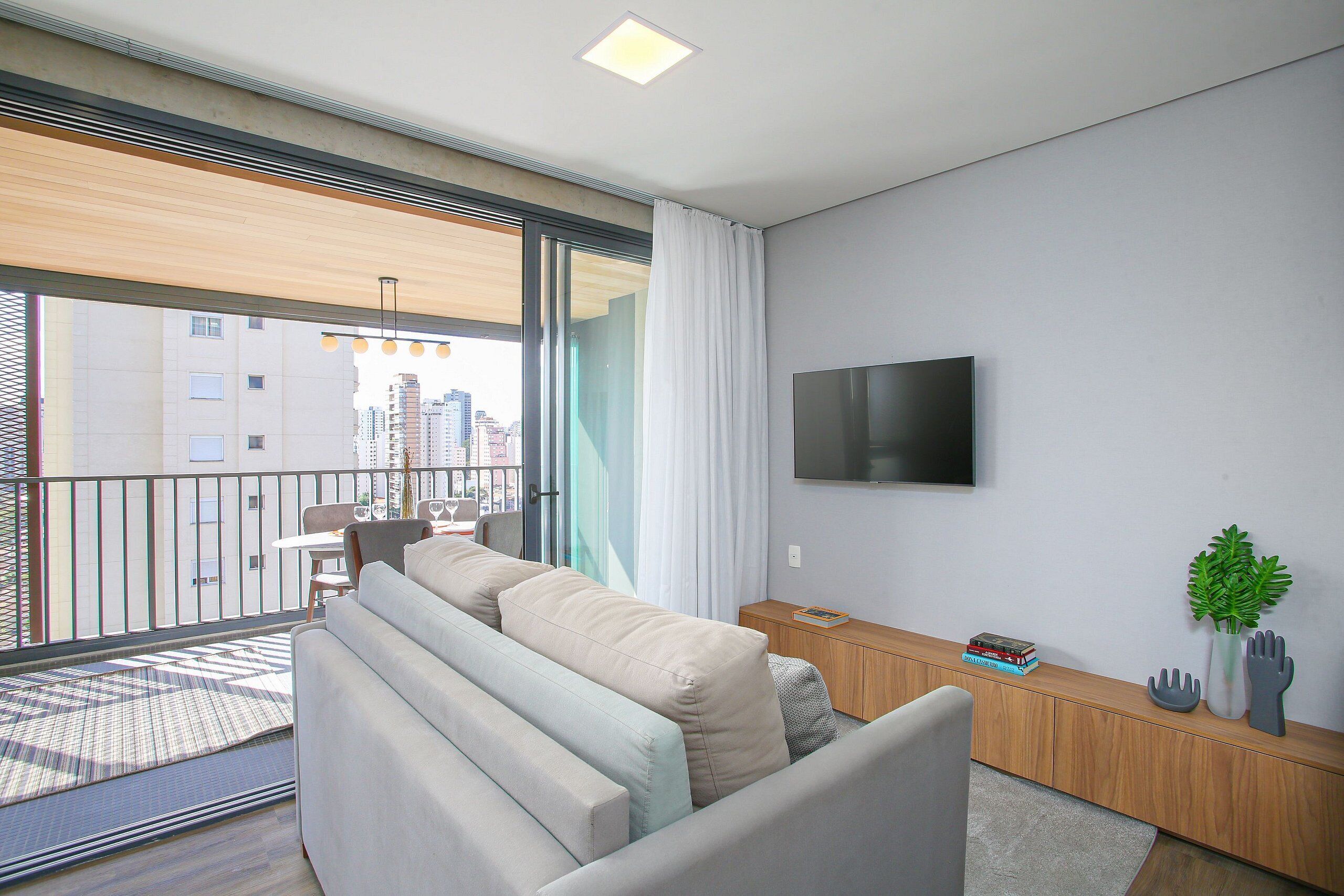 Uma sala de estar moderna com um sofá, uma televisão, uma mesinha e um vaso de planta.