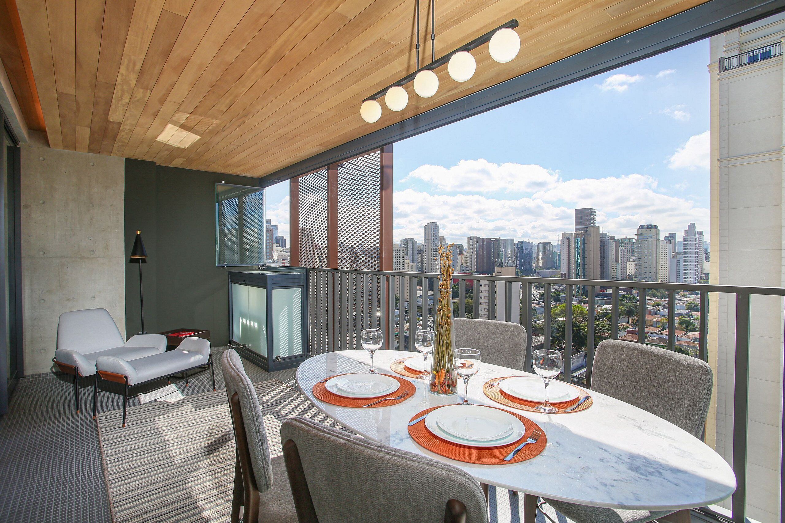 Een moderne eetruimte met uitzicht op de stad, een balkon met een hekwerk en een tafel voor vier personen.