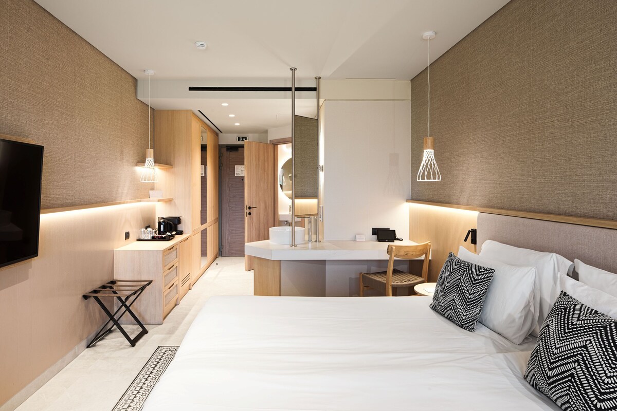 Una habitación de hotel moderna con una cama grande, un escritorio, un espejo y un televisor.