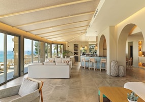 Un interno moderno con un'ampia zona soggiorno, una cucina con sgabelli da bar e vista mare.