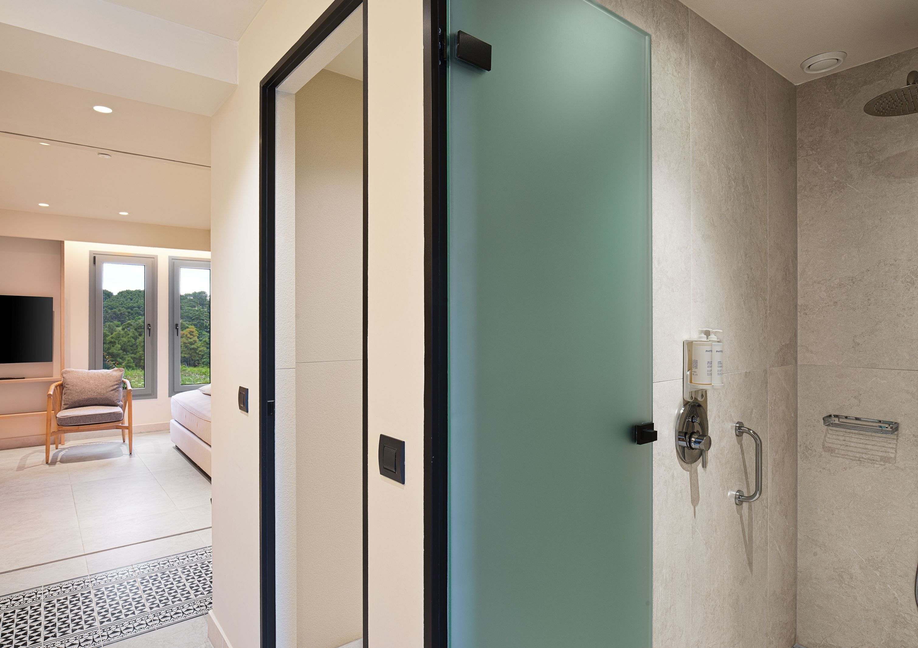 A modern bathroom with a glass shower door, a handheld showerhead, and a towel rack.