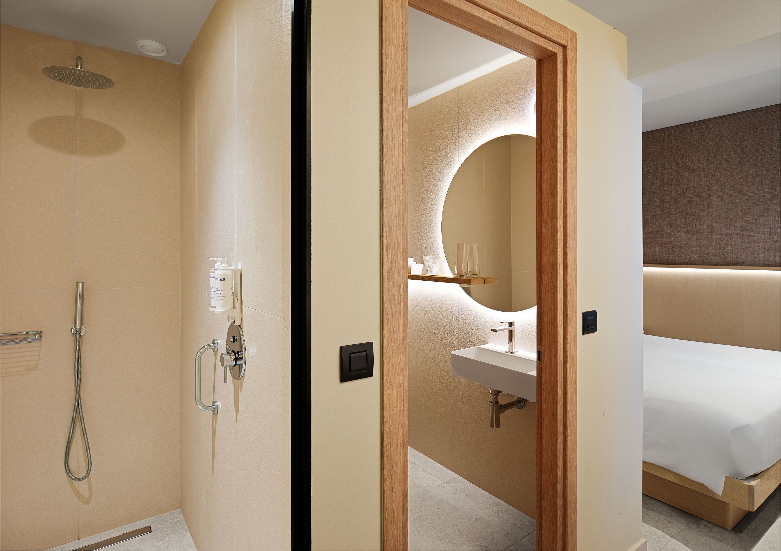 A hotel room with a shower, a sink, a mirror, and a bed.