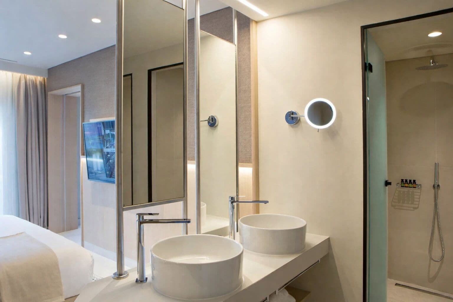 A modern bathroom with two sinks, a large mirror, and a glass shower enclosure.