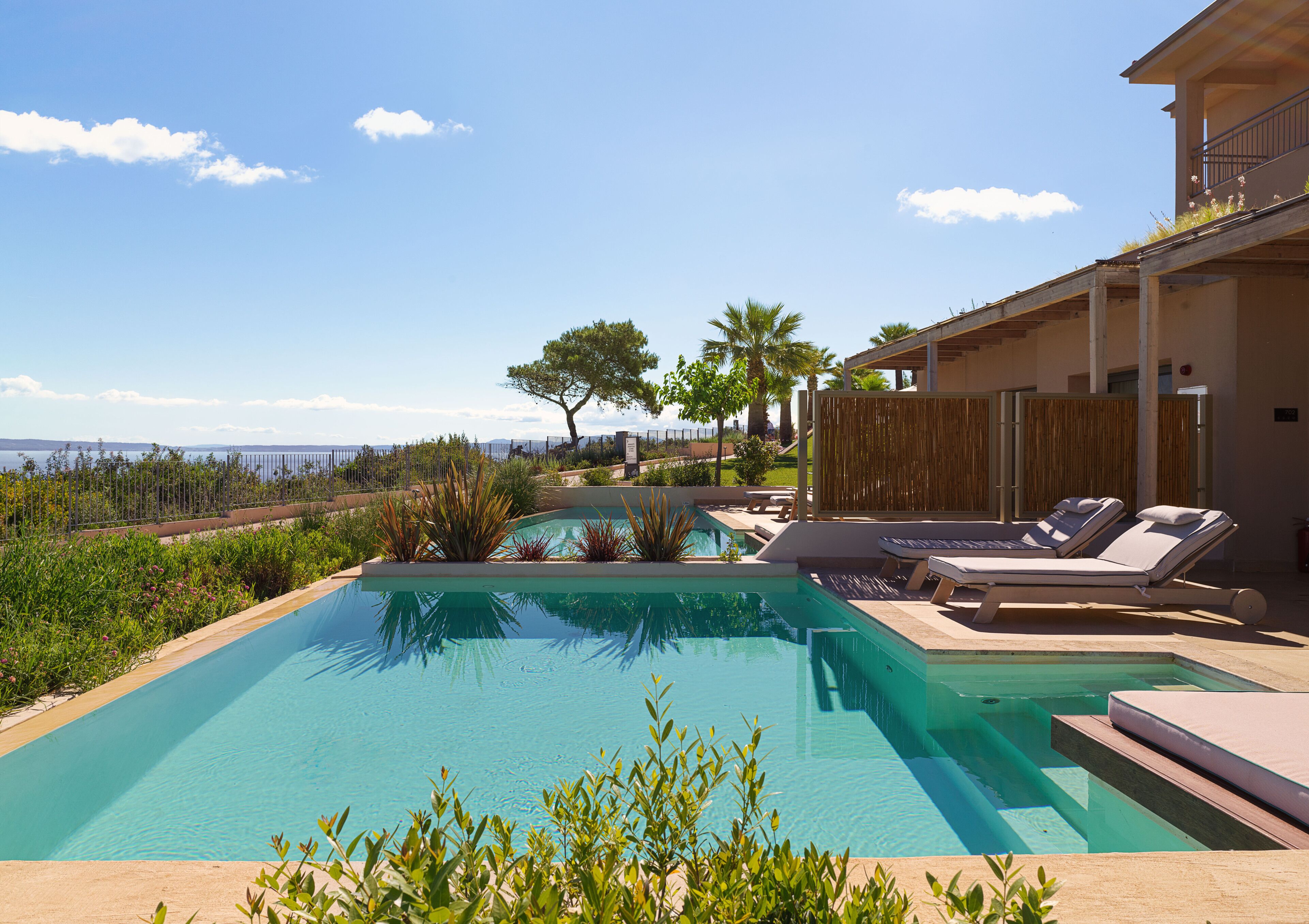 A swimming pool with lounge chairs and a view of the sea.