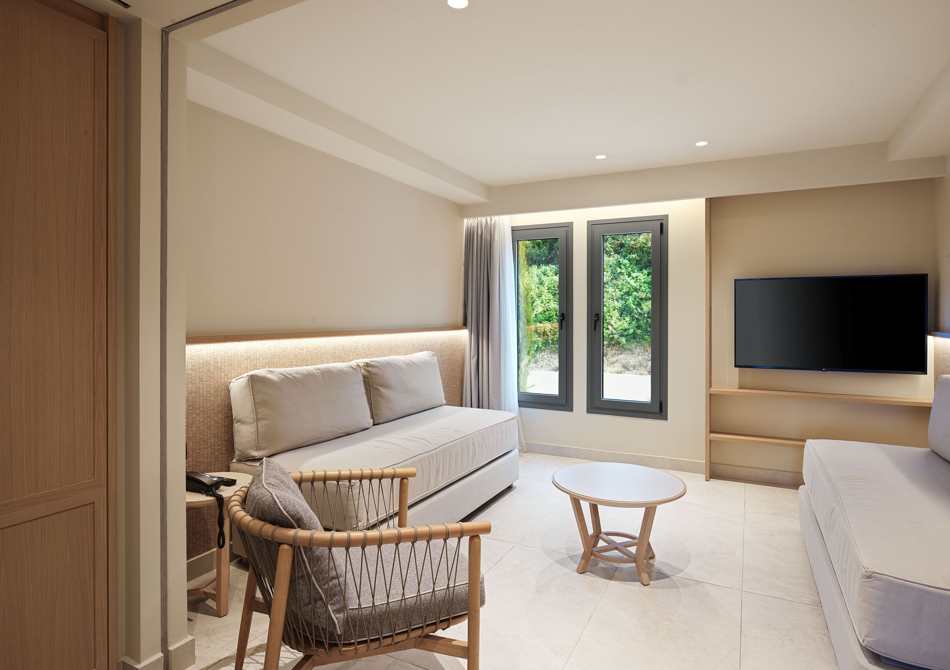 A modern bedroom with a bed, a TV, a small table, and a chair.