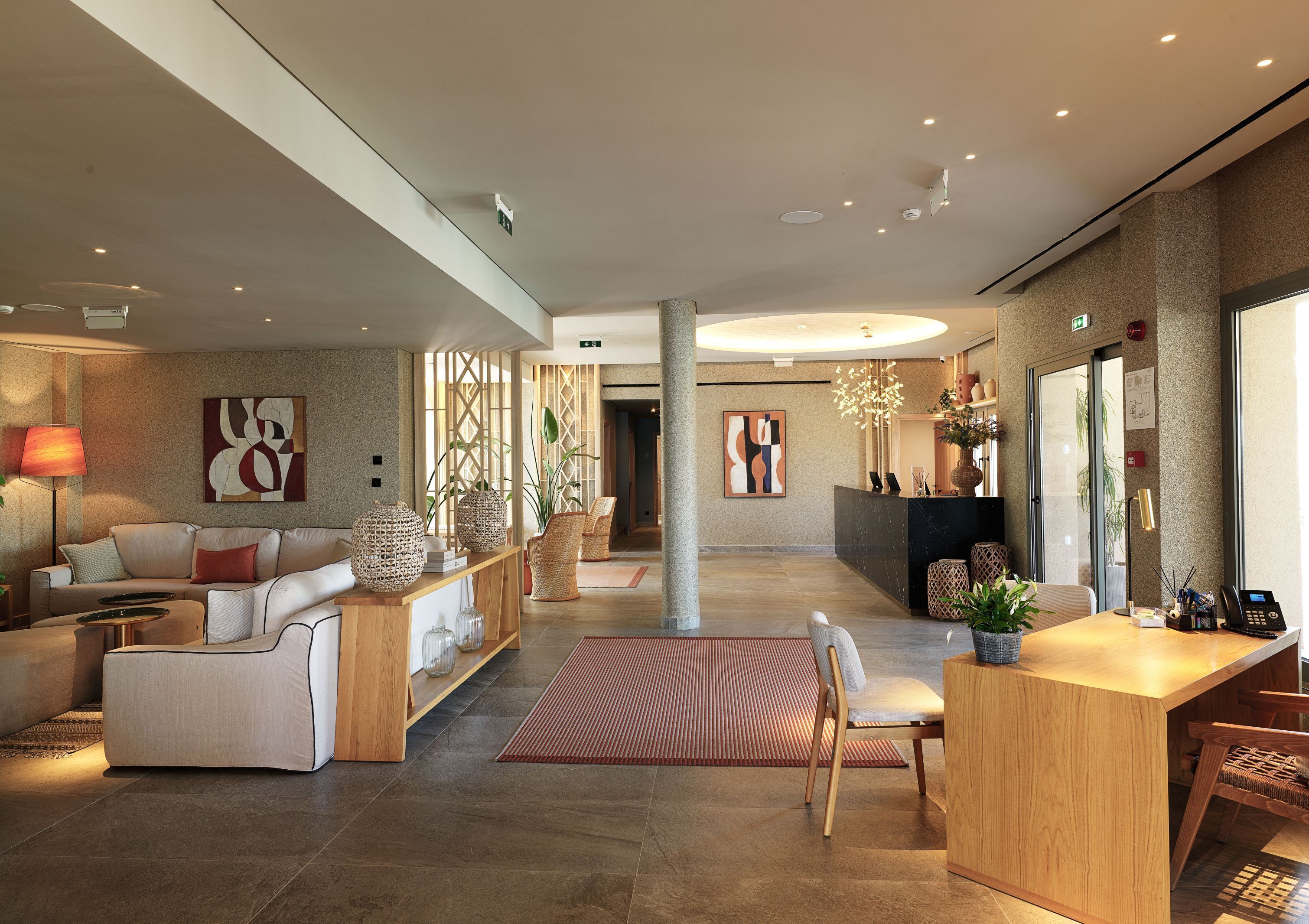 A modern hotel lobby with a reception desk, seating area, and decorative elements.
