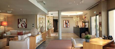 A modern hotel lobby with a reception desk, seating area, and decorative elements.