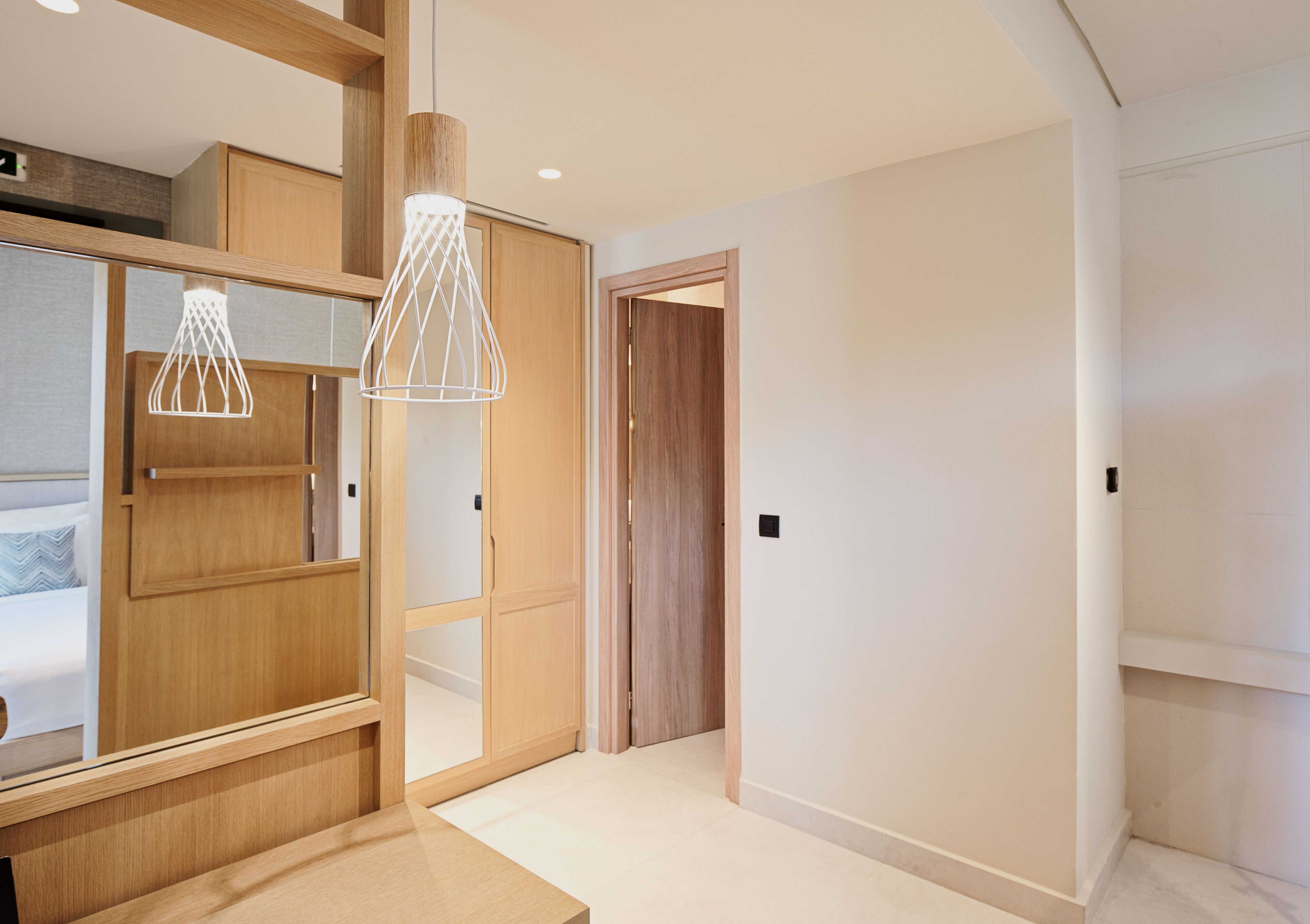 Un dormitorio moderno con un armario de madera, una cama con almohada estampada y una lámpara colgante.