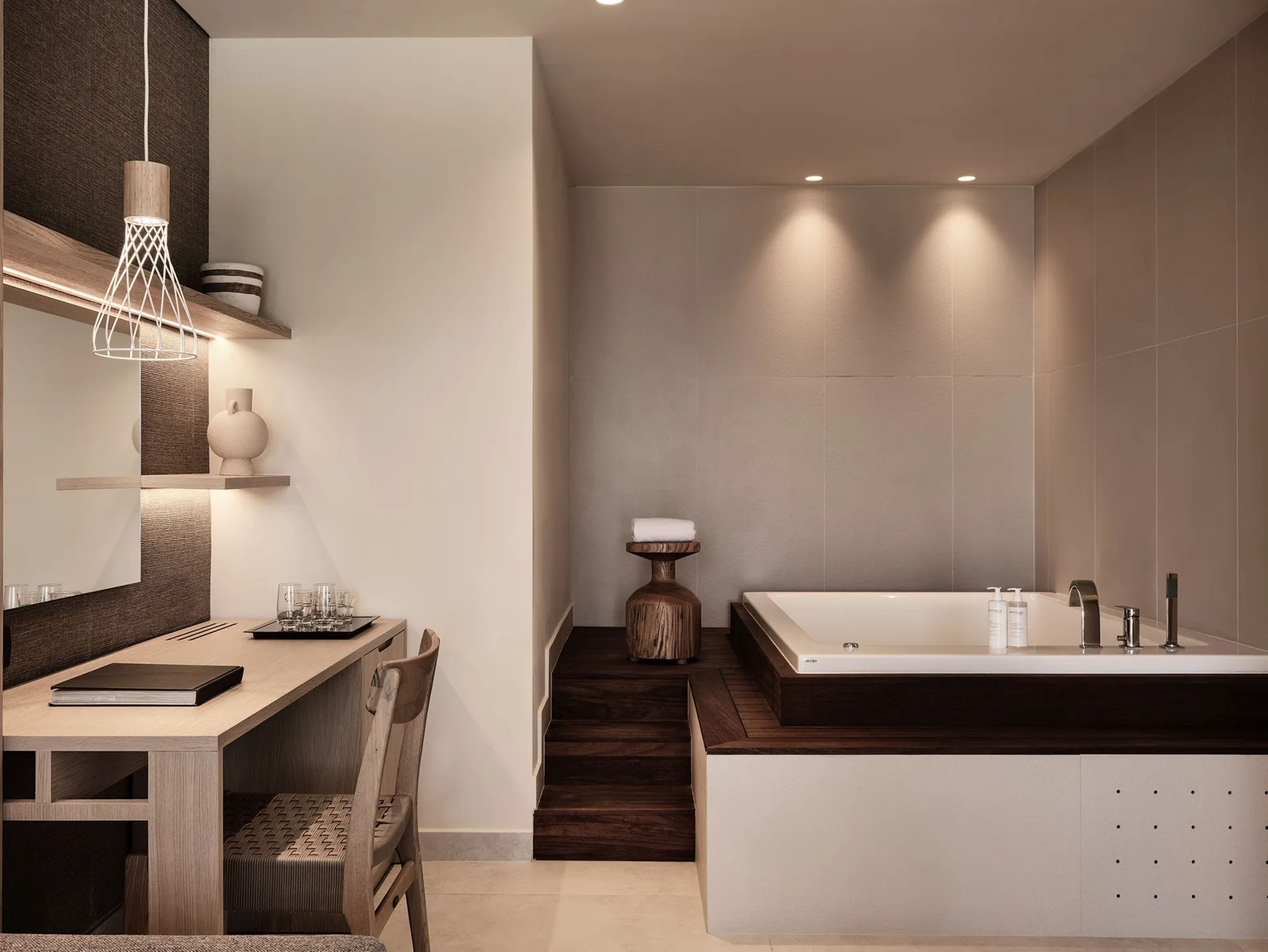 A modern bathroom with a large bathtub, a wooden vanity, and a seating area with a table and chairs.