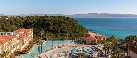 Un resort con piscina, tumbonas y vistas al mar.