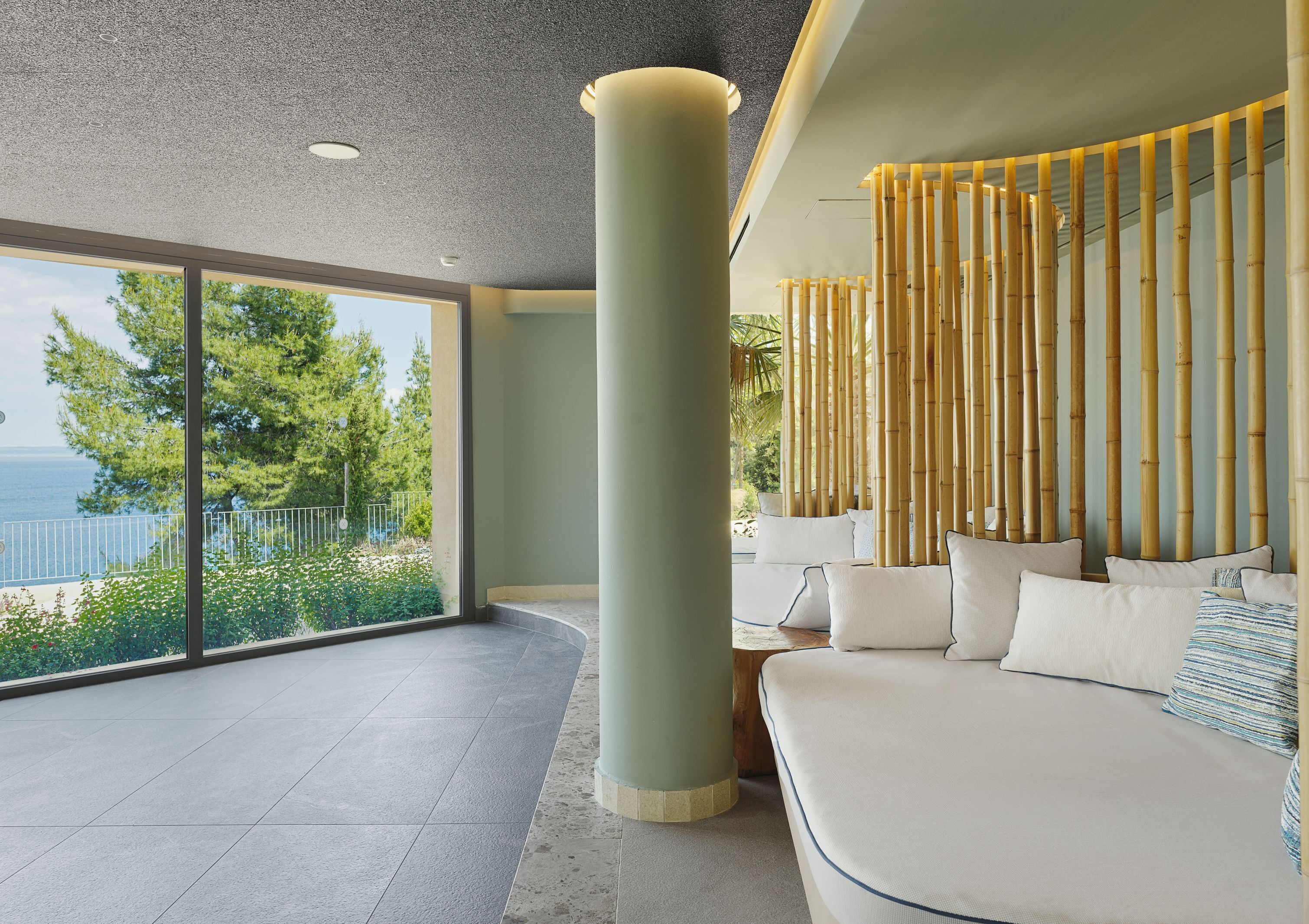 A modern interior with a large window, a curved sofa, and a bamboo wall feature.