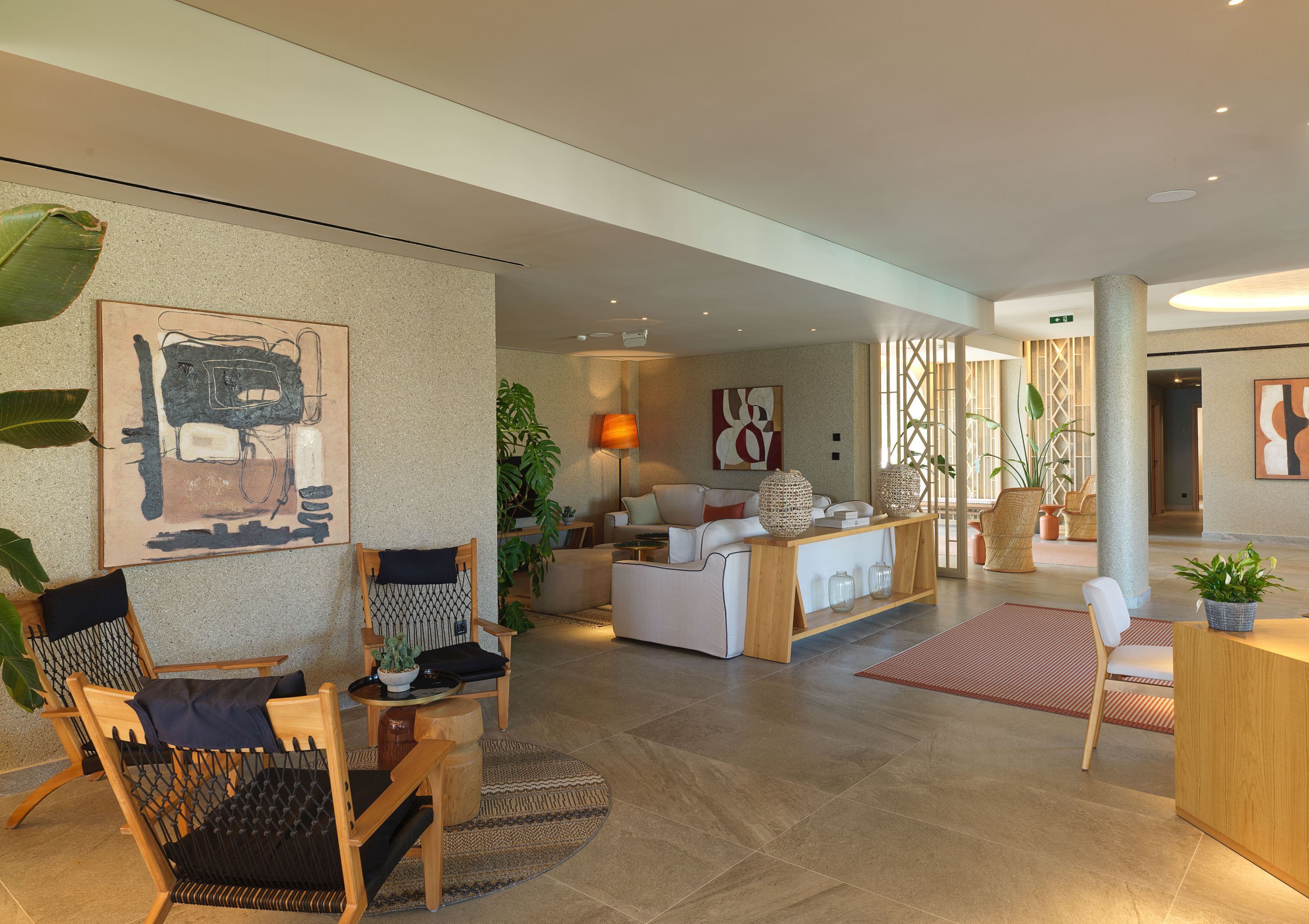 Un moderno vestíbulo de hotel con una zona de estar, un mostrador de recepción y obras de arte en las paredes.