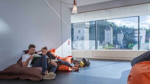 Un interior moderno con ventanas amplias, un techo alto y vistas a un castillo.