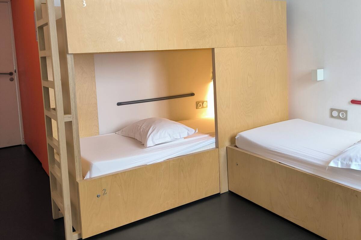 Une chambre avec un lit superposé, comprenant deux lits, une échelle en bois et un petit placard.