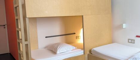 Dormitorio con literas, una escalera de madera y un mueble pequeño.