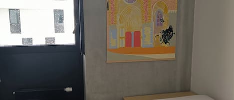 A room with a bed, a window, and a wall-mounted painting.