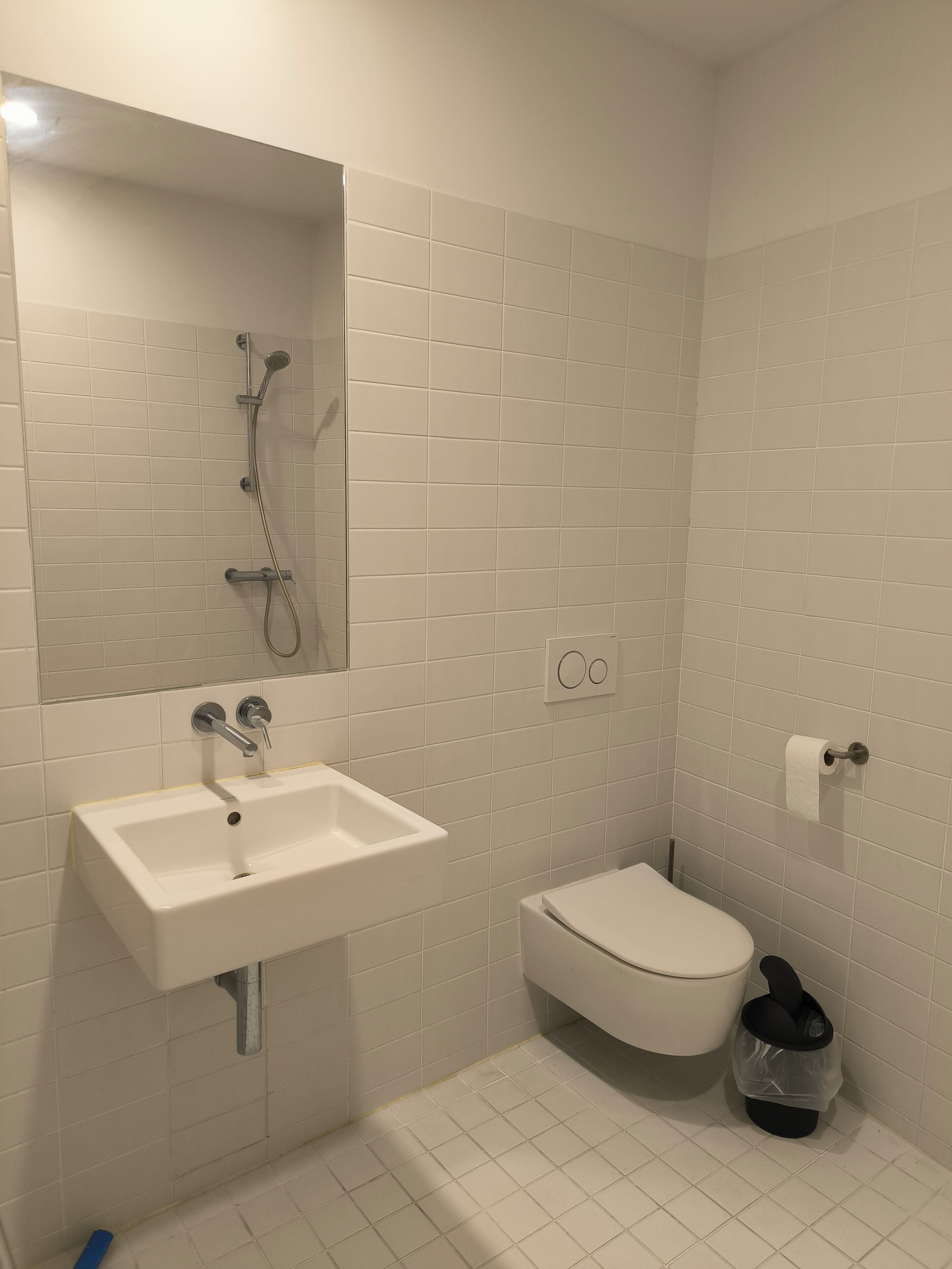 Une salle de bain avec un lavabo blanc, des toilettes, une douche et un miroir.