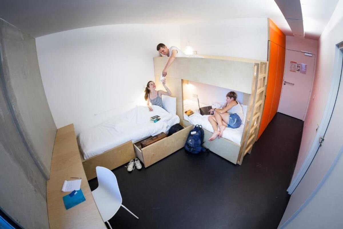Une chambre de dortoir avec des lits superposés, un bureau et une chaise.