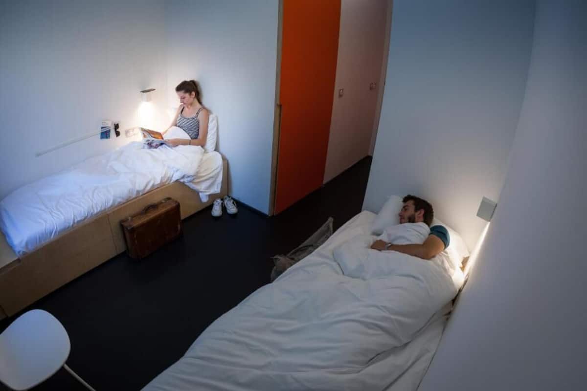 Une chambre de dortoir avec deux lits, une valise et une petite table.